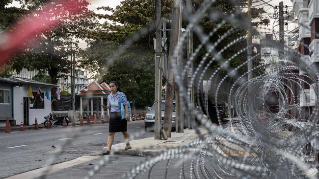 A woman walks past razor wire set up in front of the Crown Property Bureau in Bangkok on Tuesday. Picture: Getty Images