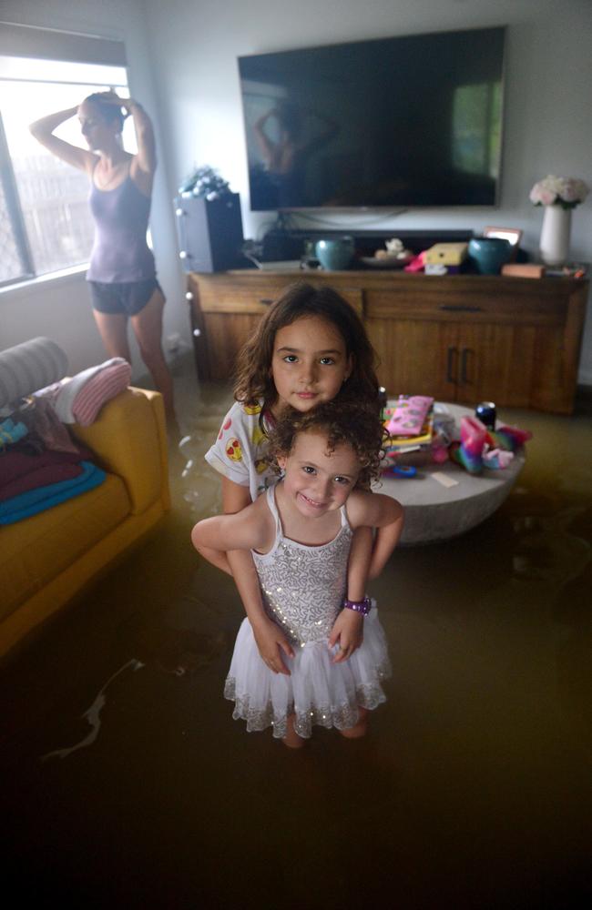 Lindle Hanran with her daughters Zara, 8, and Bailee, 4, in the flooded lounge room of their home in Laura Court, Deeragun. Picture: Evan Morgan