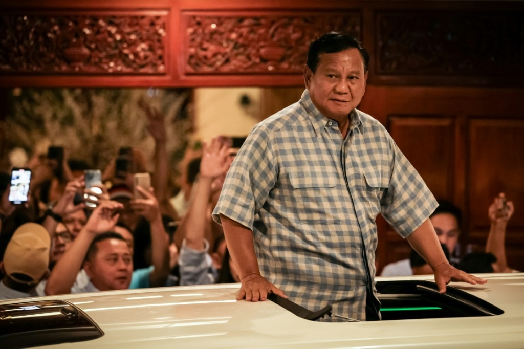 Indonesian presidential candidate Prabowo Subianto reacts to cheering supporters from a car as he leaves his residence to attend a gathering Wednesday evening