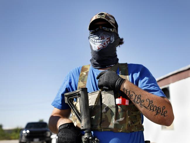 Armed protester Wyatt Winn waits for Ector County Sheriff's officers and Texas State Troopers, who were monitoring a protest, shortly before his arrest Monday, May 4, 2020, at Big Daddy Zane's bar near Odessa, Texas. Winn and others were supporting the the bar's owner, who decided to open despite orders from the Texas governor during the coronavirus pandemic that prohibit the opening until later in May. (Eli Hartman/Odessa American via AP)