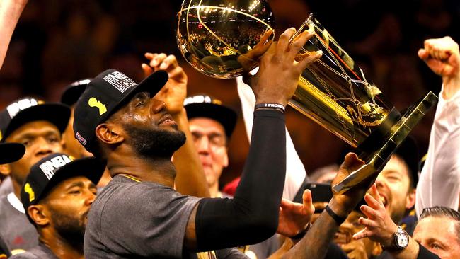 LeBron James #23 of the Cleveland Cavaliers holds the Larry O'Brien Championship Trophy.