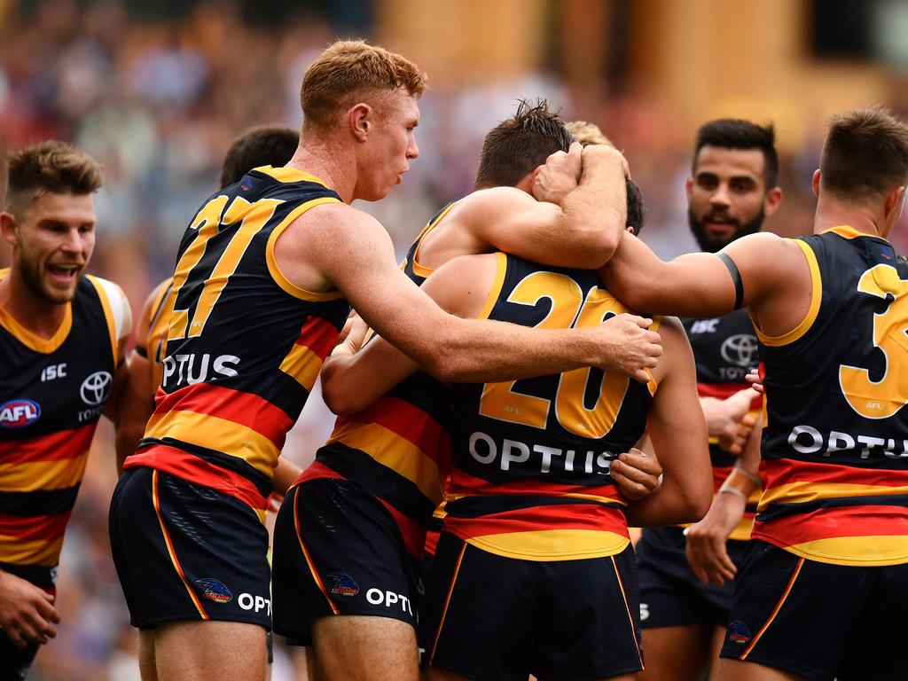 Chayce Jones is mobbed by Crows teammates after kicking his first goal in AFL footy at Adelaide Oval on Saturday. Picture: Daniel Kalisz (Getty).