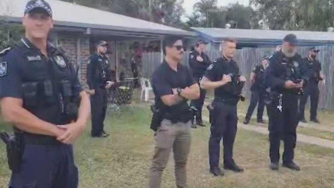 Police officers control the crowd gathered on the lawn of a Rockhampton home. Picture: Nine