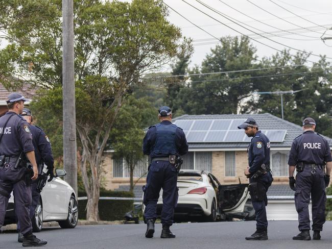 Police inspect the burnt-out remains of a vehicle used during a shooting at Bankstown Central Shopping Centre. Picture: Brook Mitchell/Getty Images.