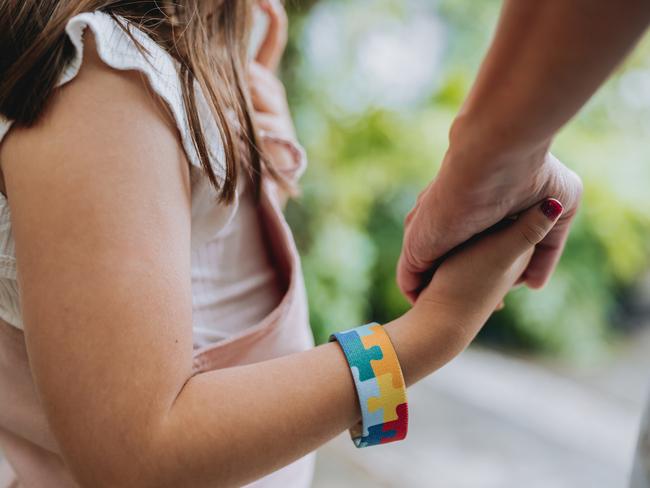 Autistic child holding hands with his mother