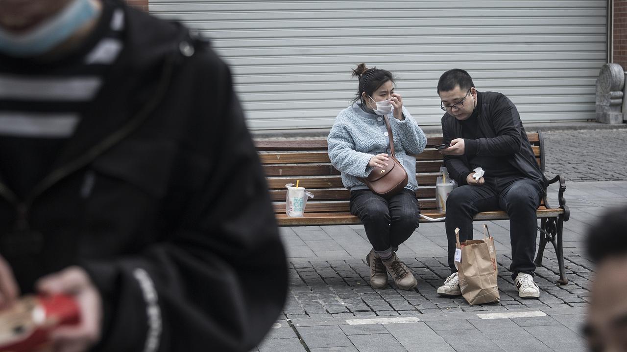 Residents of Wuhan eat McDonald’s on a bench on Monday. Picture: Getty Images