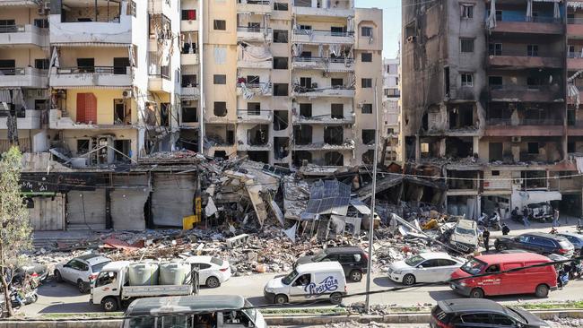 Cars drive past buildings that were damaged or destroyed in Israeli strikes in Beirut's southern suburbs on Monday. Picture: AFP