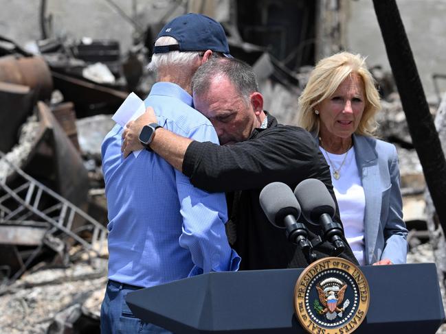 TOPSHOT - US President Joe Biden is embraced by Hawaii Governor Josh Green (C) after delivering remarks as he visits an area devastated by wildfires in Lahaina, Hawaii on August 21, 2023. The Bidens are expected to meet with first responders, survivors, and local officials following deadly wildfires in Maui. (Photo by Mandel NGAN / AFP)