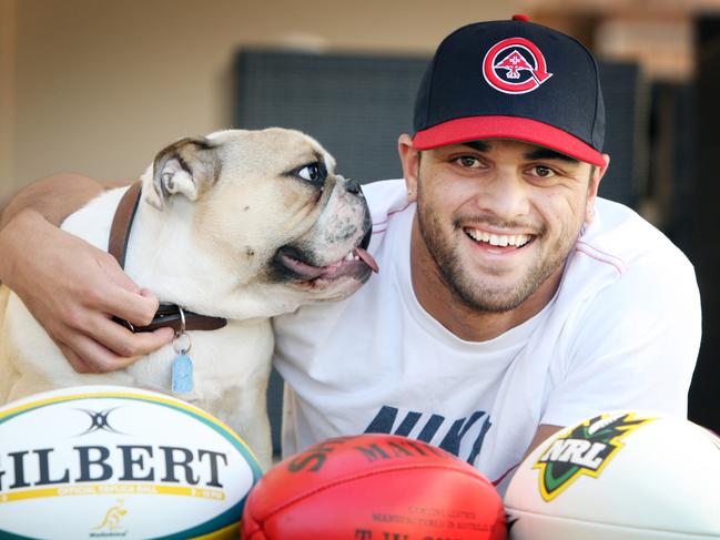 Former Brisbane Broncos NRL player Karmichael Hunt, who quit the NRL and is heading off to France to play rugby union for six months, before taking up his contract to play AFL with the fledgling Gold Coast club in 2011 season, pictured with his dog Buddha and balls from three football codes at his Calamvale home in Brisbane.