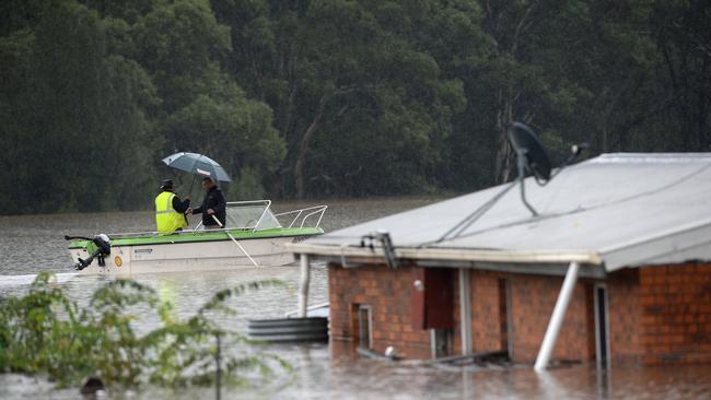 Residents row past a home that has been covered by floodwaters in the suburb of Vineyard, near Windsor, in NSW. Picture: NCA NewsWire/Jeremy Piper