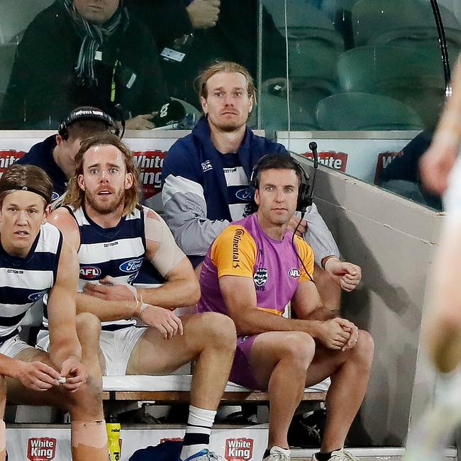 Tom Stewart of the Cats (back row) is seen sitting on the bench with the jacket on after being subbed out of the game. Picture: Dylan Burns/AFL Photos via Getty Images