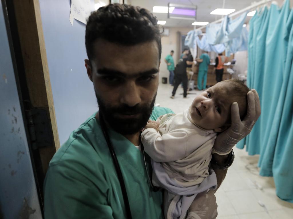 A medic carries a baby as Palestinians injured in air strikes arrive at Nasser Medical Hospital in Khan Yunis, Gaza. Picture: Ahmad Hasaballah/Getty Images