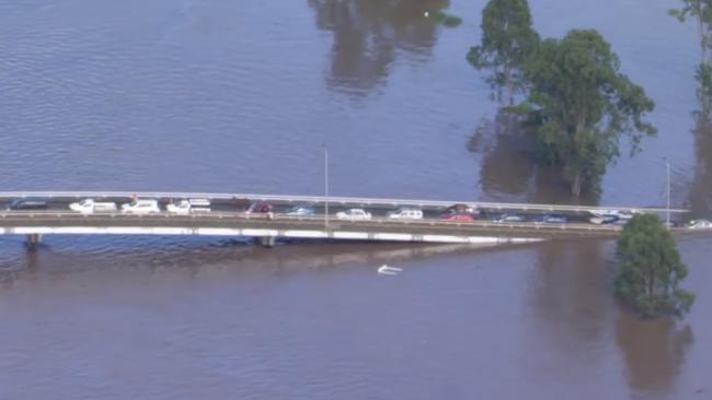 Aerial footage shows horses and more than a dozen cars stranded on Woodburn Bridge, about 34km south of flood-devastated Lismore. Images: Seven