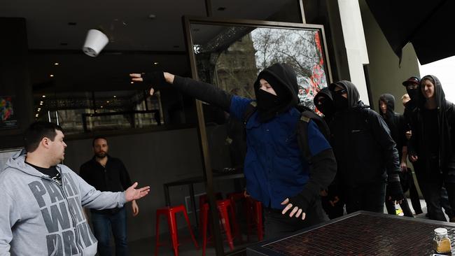 An anti-racism protester hurls a pot plant at United Patriot Front protesters. Picture: Jake Nowakowski