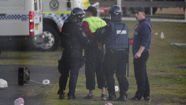 Riot police lead a detainee away in handcuffs during a riot at the Frank Baxter Juvenile Justice Centre, Kariong. Picture: AAP /Bianca De Marchi.