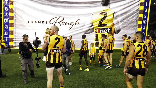 Jarryd Roughead of the Hawks carries his daughter Pippa through the banner