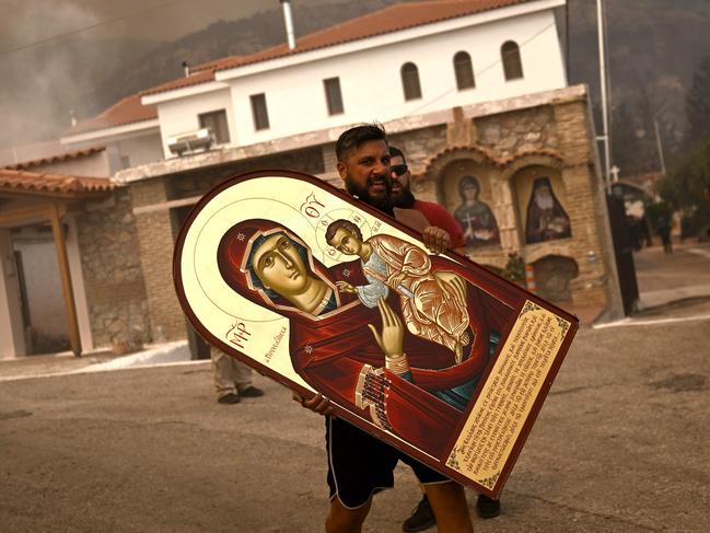 CORRECTION / A volunteer carries an icon from a burning monastery as a wildfire spreads in Acharnes, north of Athens, on August 23, 2023. Greek firefighters on August 23, 2023 struggled to contain uncontrolled fires throughout the country for a fifth day, several of them bordering an acrid, smoke-filled Athens. (Photo by Angelos Tzortzinis / AFP) / âThe erroneous mention[s] appearing in the metadata of this photo by Angelos Tzortzinis has been modified in AFP systems in the following manner:[Acharnes] instead of [Archanes]. Please immediately remove the erroneous mention[s] from all your online services and delete it (them) from your servers. If you have been authorized by AFP to distribute it (them) to third parties, please ensure that the same actions are carried out by them. Failure to promptly comply with these instructions will entail liability on your part for any continued or post notification usage. Therefore we thank you very much for all your attention and prompt action. We are sorry for the inconvenience this notification may cause and remain at your disposal for any further information you may require.â