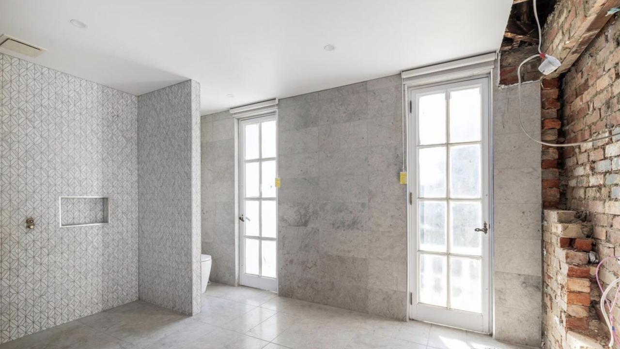 Mid-renovation and incomplete, the bathroom now reveals exposed plumbing and plaster, one of several spaces requiring extensive cosmetic work.