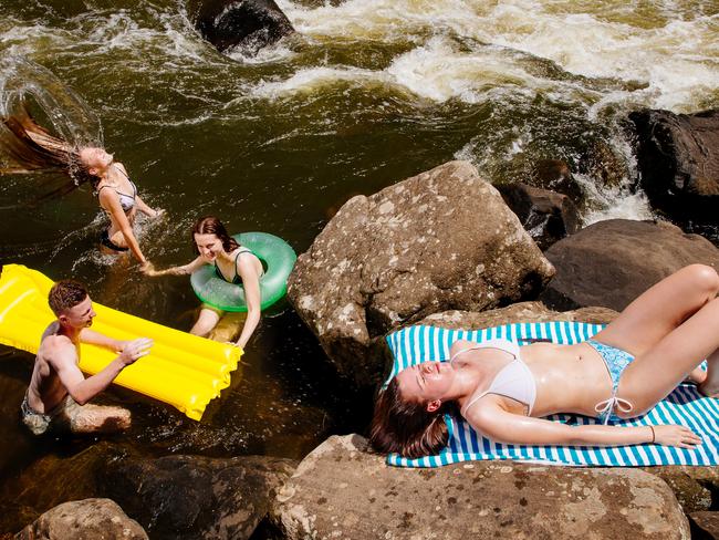 Jamie-Lee Hazes, 21, sunbathing with from left Tiarne McDonald, 17, Nathan Baker, 17, and Alisha Hazes, 17, cooling off at Bents Basin in Greendale. Picture: Jonathan Ng