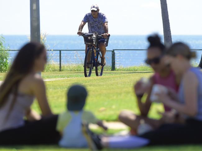 A man rides is bike along the Nightcliff foreshore as a group of people chat on the grass in Darwin, Friday, May 1, 2020. Northern Territory becomes the first state to ease COVID-19 restrictions. (AAP Image/Patrina Malone) NO ARCHIVING