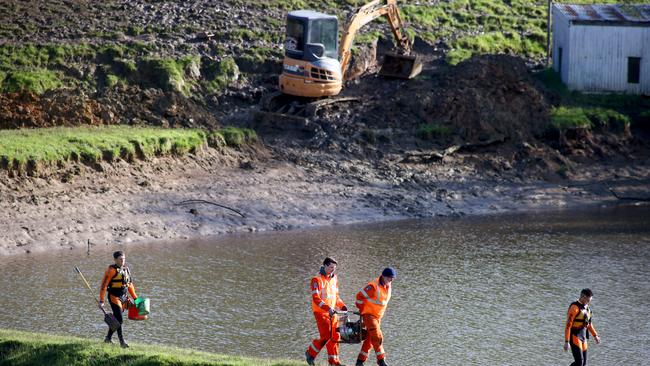 SES volunteers on Thursday morning on the edge of the dam at Echunga after a night of reducing the water levels. Picture: Kelly Barnes