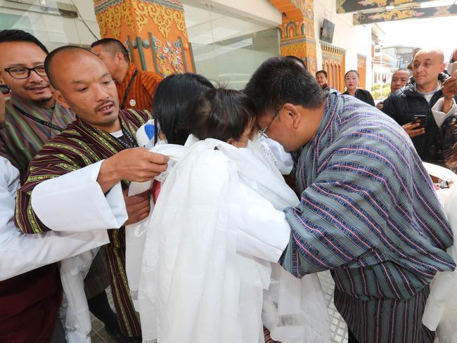 Bhumchu Zangmo holds the twins with father Sonam Tshering [left] and the twins’ uncle and aunt hug them upon arrival. Picture: Alex Coppel