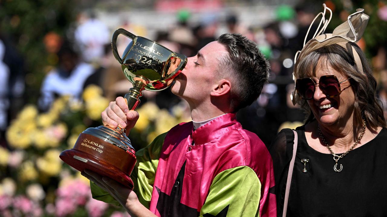 Irish jockey Robbie Dolan kisses the trophy next to trainer Sheila Laxon after riding Knight's Choice to victory in the Melbourne Cup