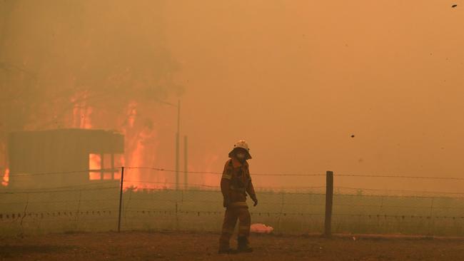 Fire and smoke dwarf an RFS crew battling blazes along the Old Hume Highway near the town of Tahmoor. Picture: Dean Lewins/AAP