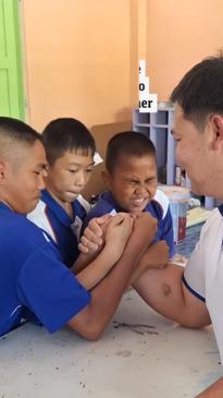 Students try to beat their teacher in an arm wrestle