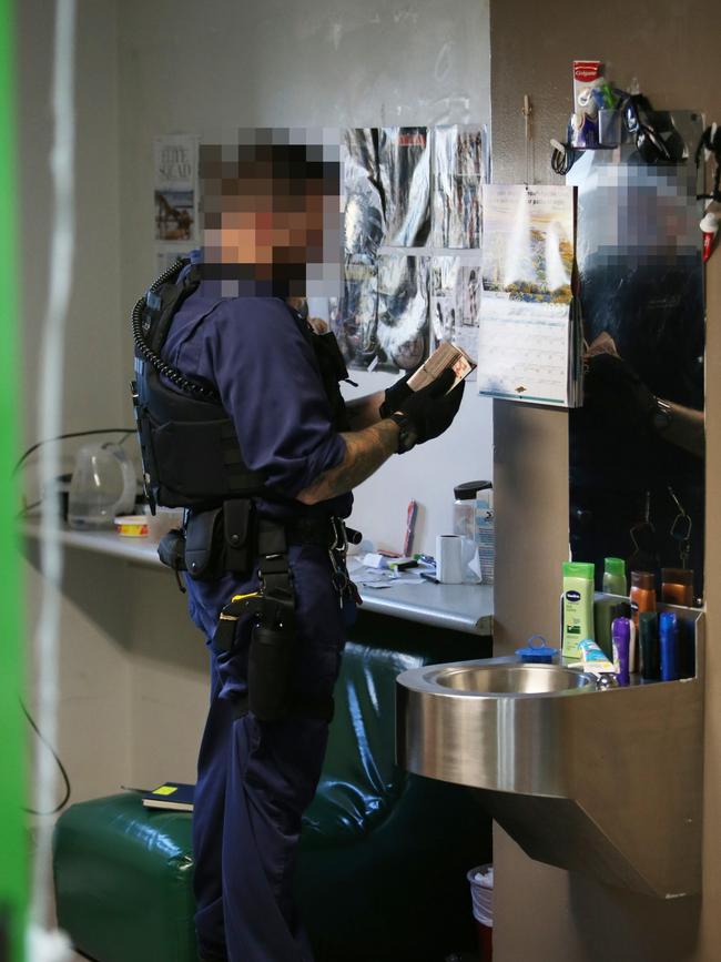 An officer overturns an inmate’s room on the search for contraband. Picture: Peter Lorimer