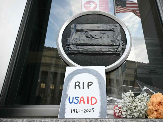 TOPSHOT - Tributes are placed beneath the covered seal of the US Agency for International Development (USAID) at their headquarters in Washington, DC, on February 7, 2025. US President Donald Trump on February 7, 2025 called for USAID to be shuttered, escalating his unprecedented campaign to dismantle the humanitarian agency. (Photo by Mandel NGAN / AFP)