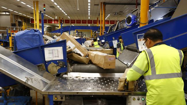 An Australia Post worker checking packages at the group’s warehouse at Granville in Sydney. Picture: Richard Dobson