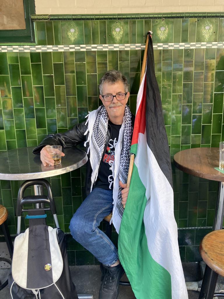 While not participating in the March, a man wearing a keffiyeh showed his solidarity with the cause by holding a Palestinian flag in one hand and a drink in the other. Picture: NewsWire