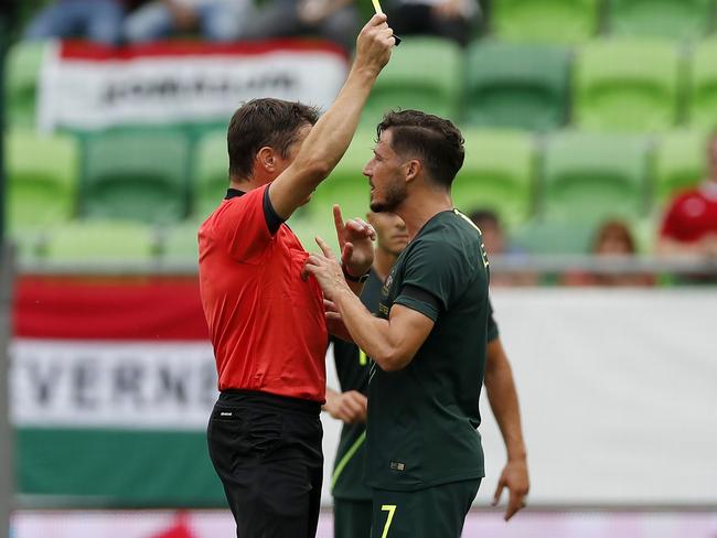 Referee Matej Vidali shows a yellow card for Mathew Leckie of Australia