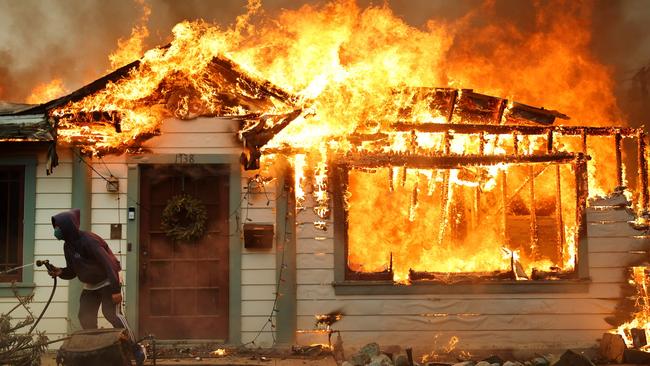 A person uses a garden hose in an effort to save a neighbouring home from catching fire during the Eaton Fire on January 8, 2025 in Altadena, California. Photo: Getty Images via AFP