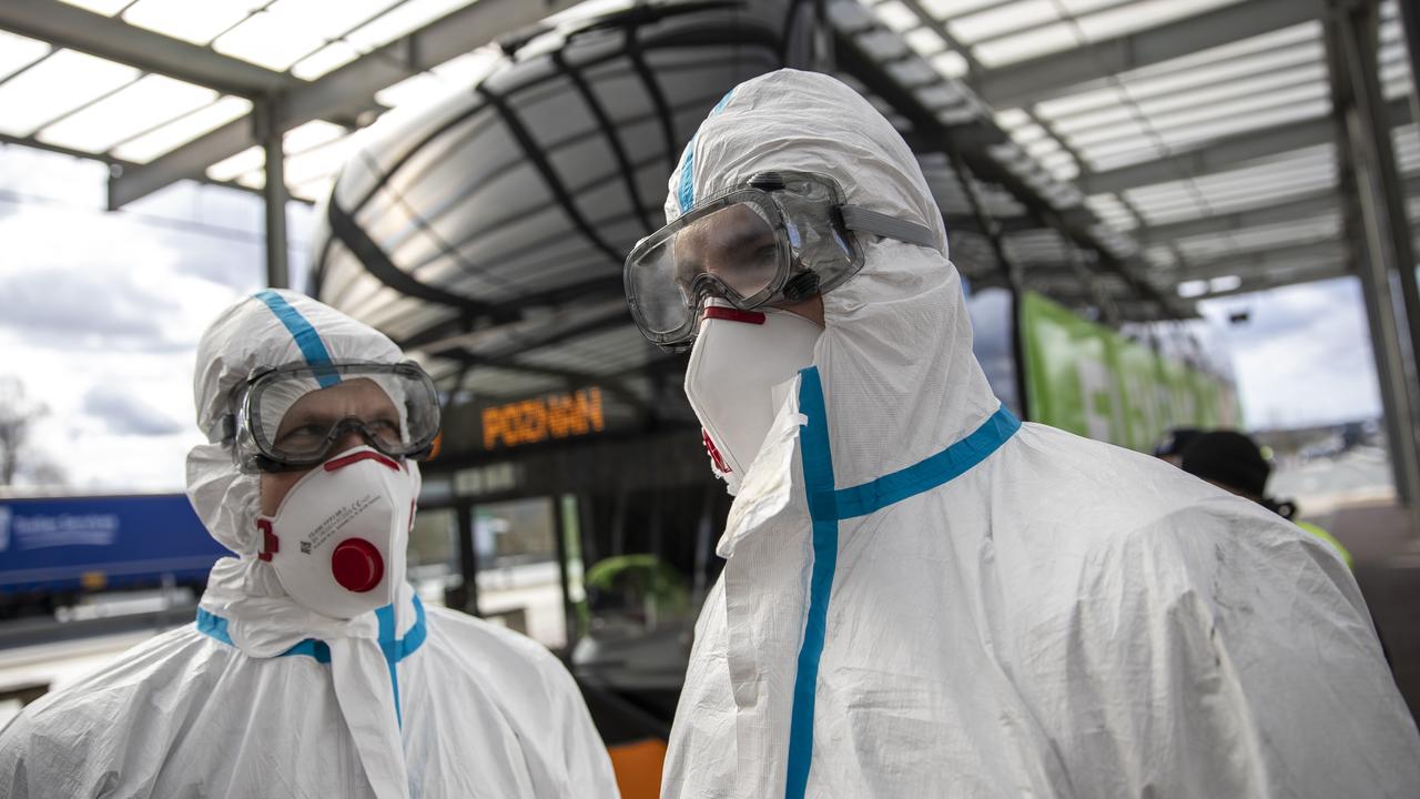 Health workers wear a protective mask and suit as they stands next to a bus to screen passengers temperature at the German-Polish border. Picture: Maja Hitij/Getty Images