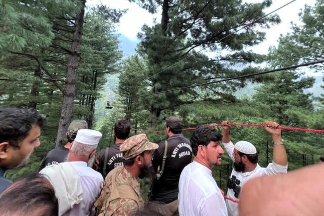 A handout photograph from Pakistan's Inter Service Public Relation wing shows servicemen using a zipline to reach a cable car stranded over a valley