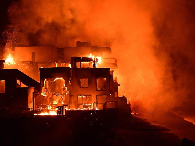 TOPSHOT - A beach house is engulfed in flames as the Palisades Fire burns along Pacific Coast Highway in Malibu, California, on January 8, 2025. At least five people have been killed in wildfires rampaging around Los Angeles, officials said on January 8, with firefighters overwhelmed by the speed and ferocity of multiple blazes -- including in Hollywood. (Photo by AGUSTIN PAULLIER / AFP)