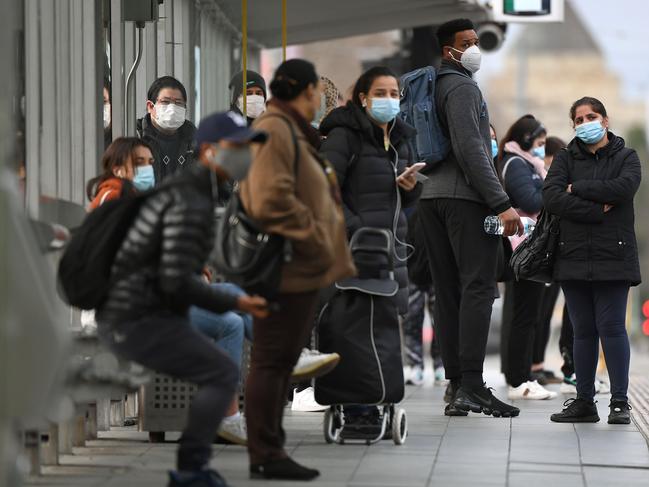 People wait for a tram at Melbourne's Flinders Street Station on July 23, 2020 on the first day of the mandatory wearing of face masks in public areas as the city experiencess an outbreak of the COVID-19 coronavirus. (Photo by William WEST / AFP)