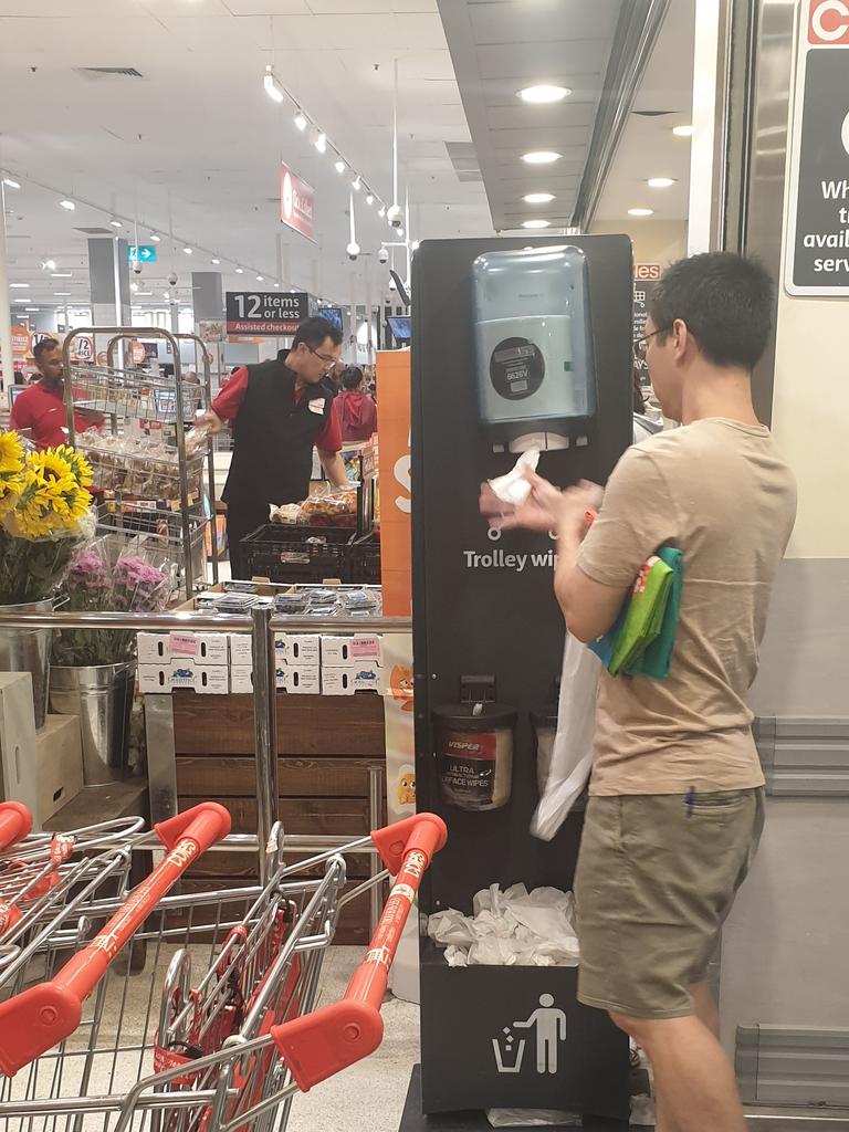 Customers lined up to wipe down their trolleys.