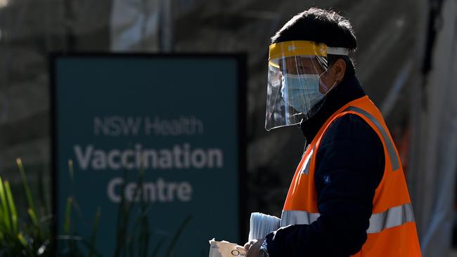 A NSW Health worker in PPE hands out masks and hand sanitiser at the NSW Health COVID-19 Vaccination Hub at Sydney Olympic Park in August, 2021. Picture: Bianca De Marchi