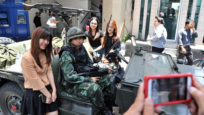 Passers-by with soldiers guarding a city centre street in Bangkok. Picture: Getty