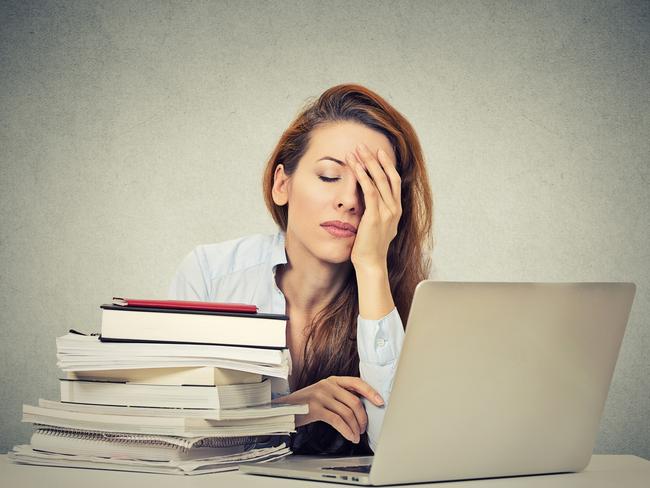 Too much work tired sleepy young woman sitting at her desk with books in front of laptop computer isolated grey wall office background. Busy schedule in college, workplace, sleep deprivation concept