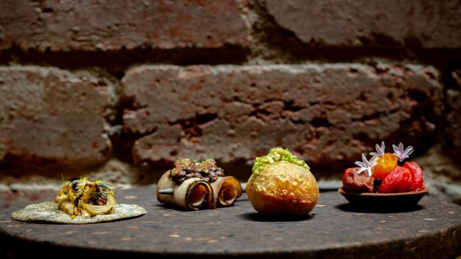 Selection of snacks Lume: hempseed cracker with fennel, BBQ pork skewer, onion doughnut and the tomato tart.