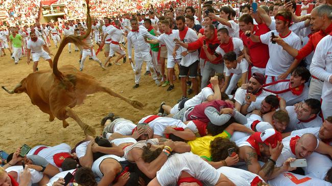 TOPSHOT - A heifer bull jumps over revellers in the bullring after the second bullrun the San Fermin festival in Pamplona, northern Spain on July 8, 2019. - On each day of the festival six bulls are released at 8:00 a.m. (0600 GMT) to run from their corral through the narrow, cobbled streets of the old town over an 850-meter (yard) course. Ahead of them are the runners, who try to stay close to the bulls without falling over or being gored. (Photo by ANDER GILLENEA / AFP)