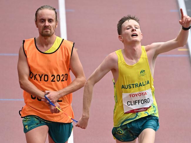 Paralympian Jaryd Clifford and his guide cross the finish line to win the men's marathon T12 event during the Tokyo 2020 Paralympic Games at the Olympic Stadium in Tokyo on September 5, 2021. Picture: Kazuhiro NOGI/AFP