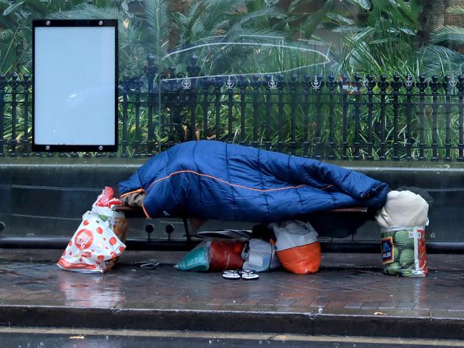 SYDNEY, AUSTRALIA - NewsWire Photos JULY 26: A person sleeps on a bus stop bench on Macquarie Street in Sydney's CBD.Picture: NCA NewsWire / Damian Shaw