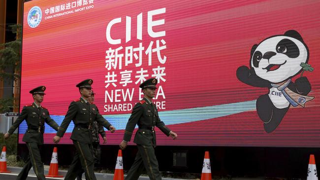 Police march past a billboard for the China International Import Expo in Shanghai. Pic: AP