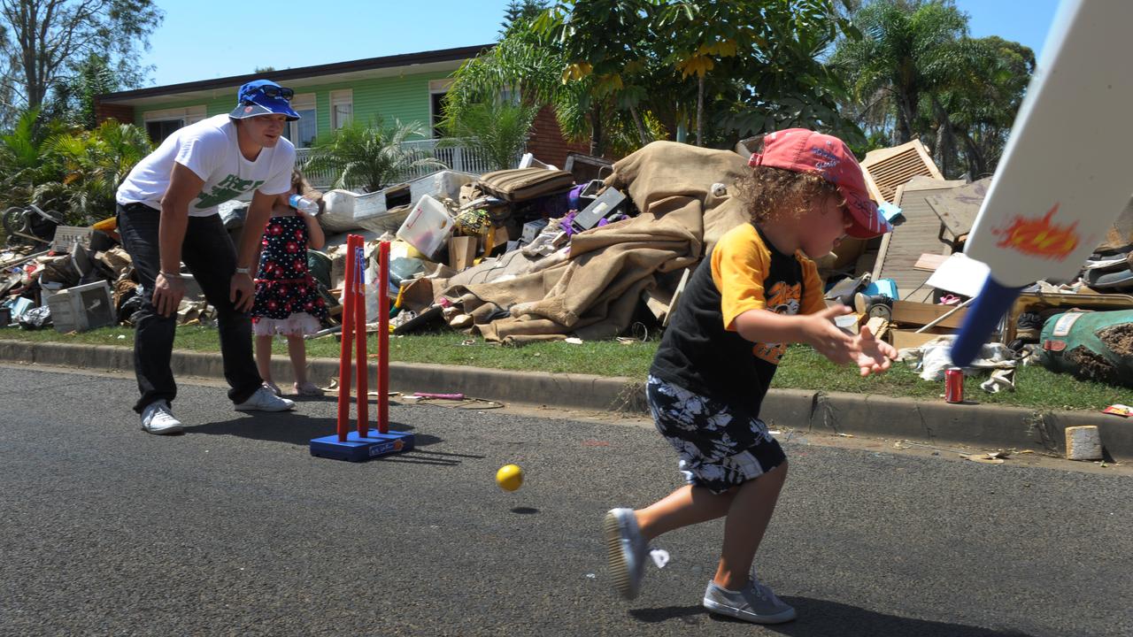 Ipswich local and Australian test cricketer Shane Watson (left) plays a game of street cricket amongst the debris with local kids in David Street in the suburb of North Booval in Ipswich, Monday, Jan. 17, 2011.