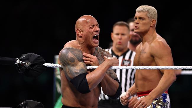 Dwayne "The Rock" Johnson reacts during a tag team fight with Romain Reigns against Cody Rhodes and Seth "Freakin" Rollins. (Photo by Tim Nwachukwu/Getty Images)